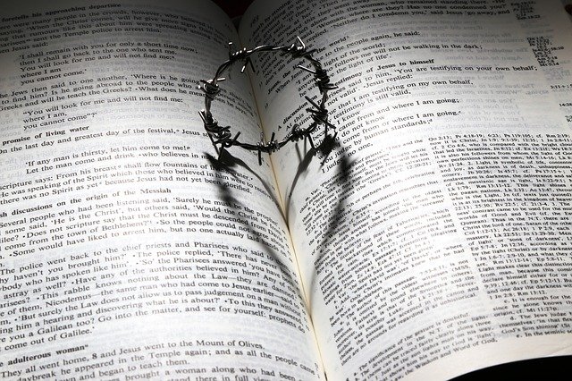 A barbed wire crown resting on a Bible casts the shadow of a heart on the Bible